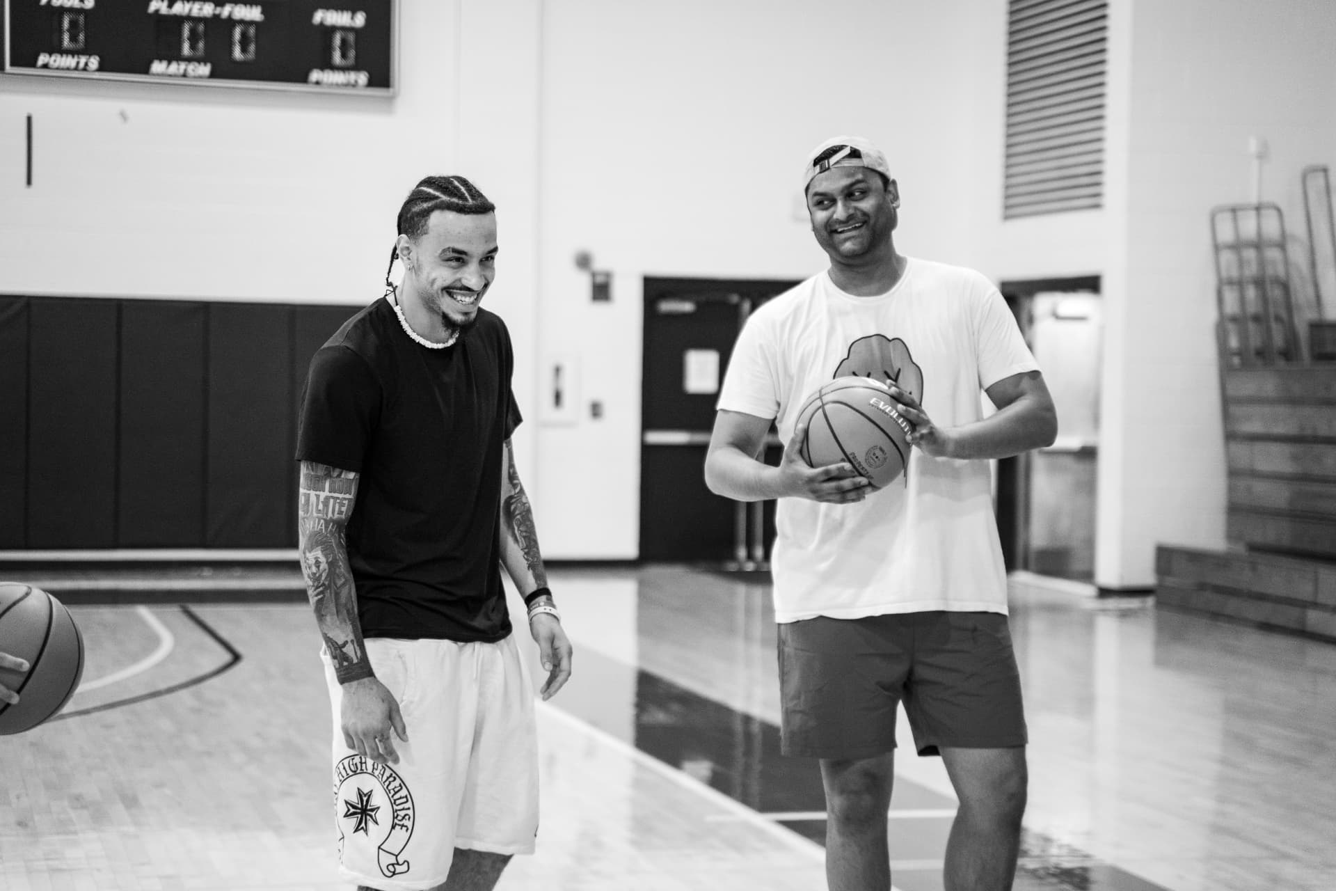 Two hoopers laughing together on an indoor court