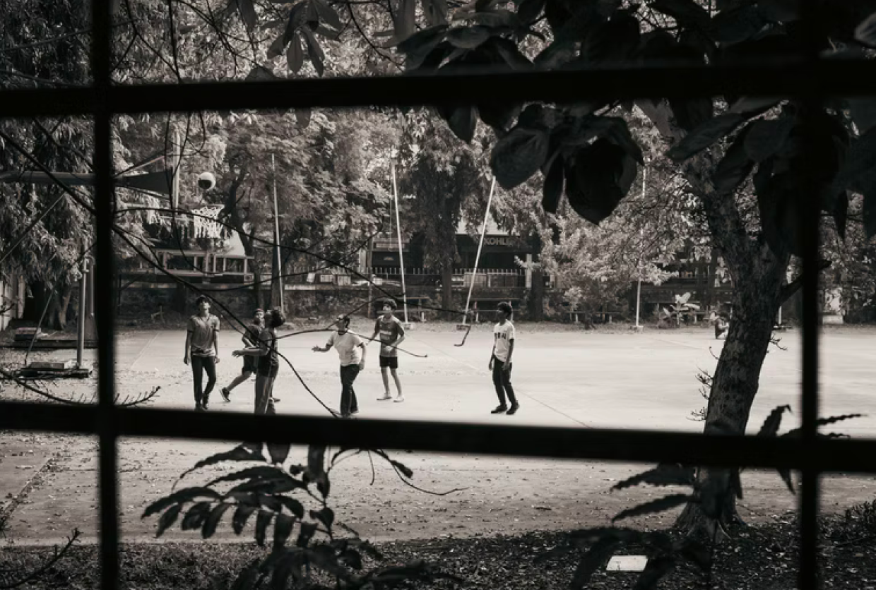 Players running a game on an outdoor court seen through a window frame
