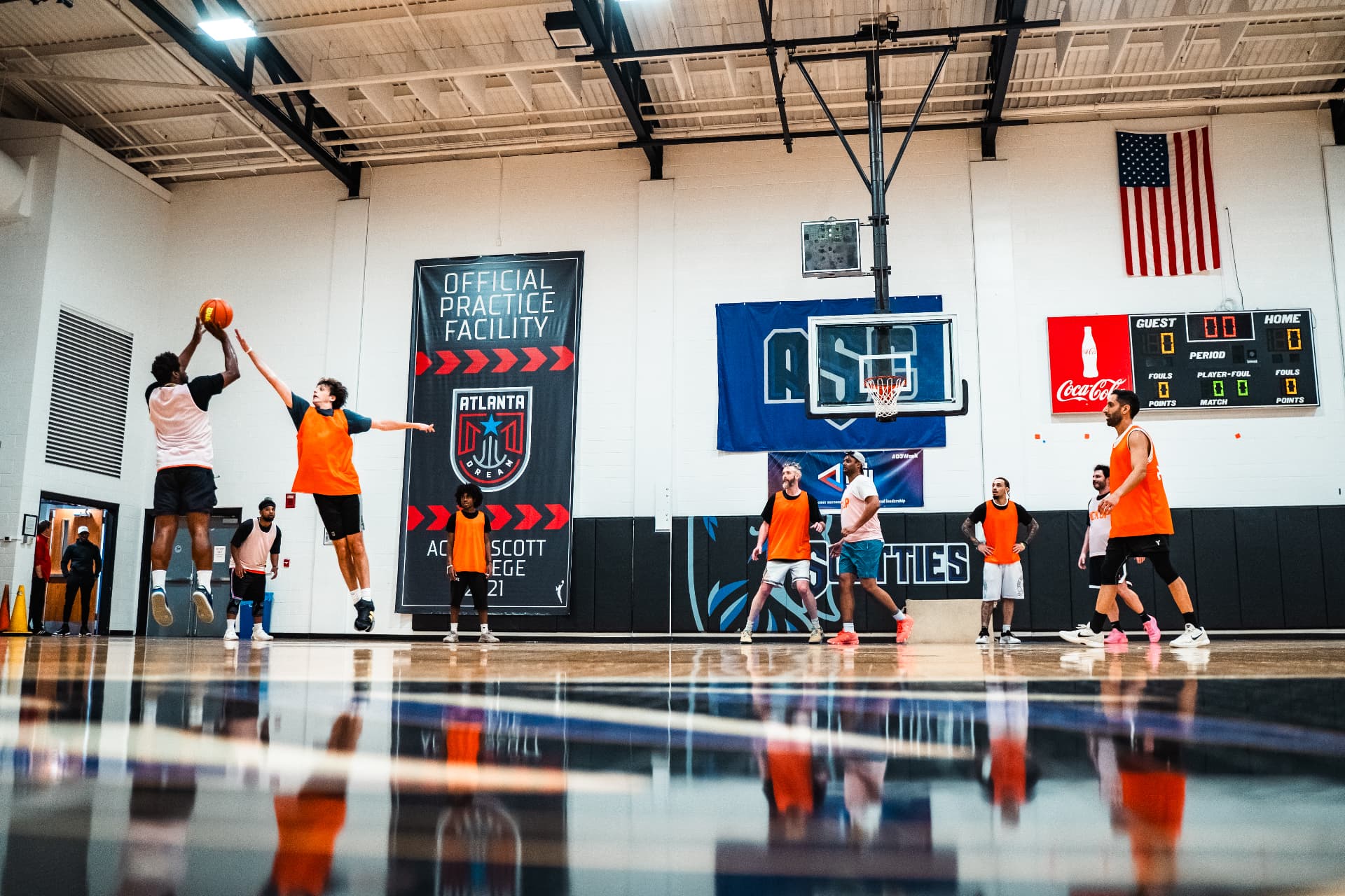 Hoopers in orange pinnies playing a pickup run in an indoor gym